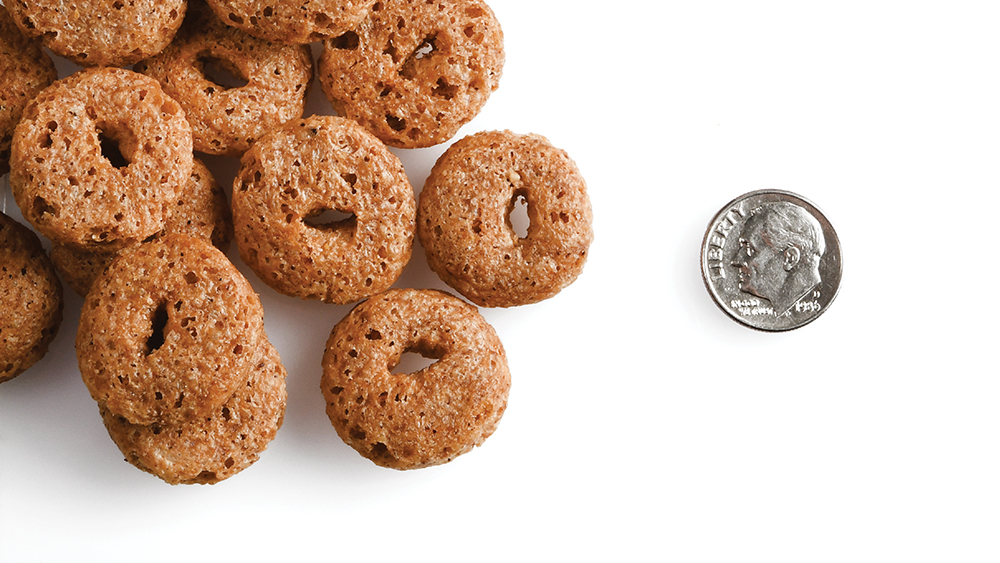 A small pile of Crunchy Os Peanut Butter Jammers treats next to a dime for scale.