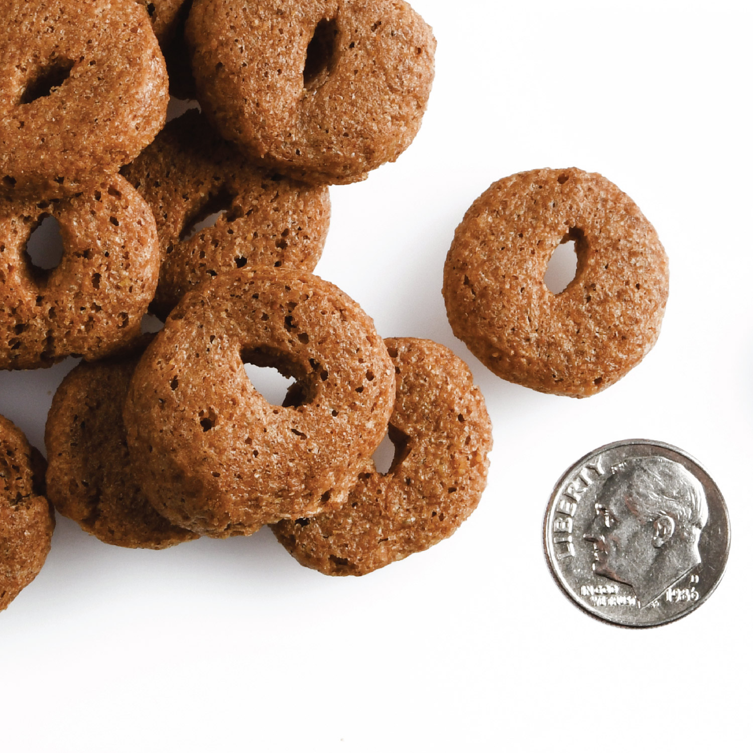 A small pile of Crunchy Os Pot Roast Punchers treats next to a dime for scale.